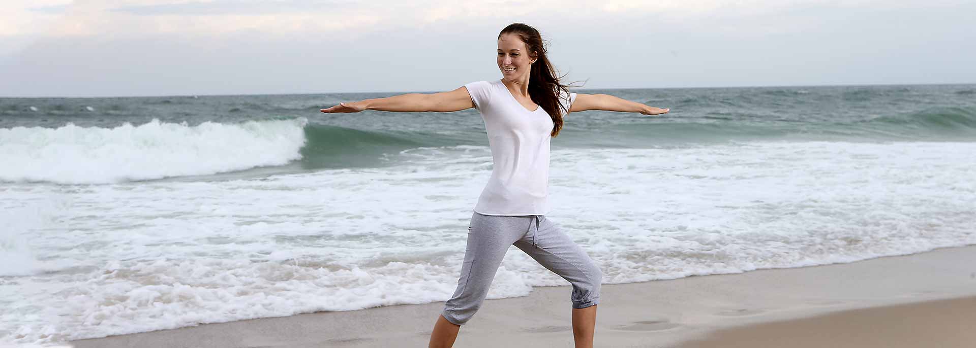 Frau macht eine Yogaübung am Strand 